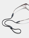 A shot of Stoggles sunglasses with a black neck cord resting on a white background, emphasizing functionality.